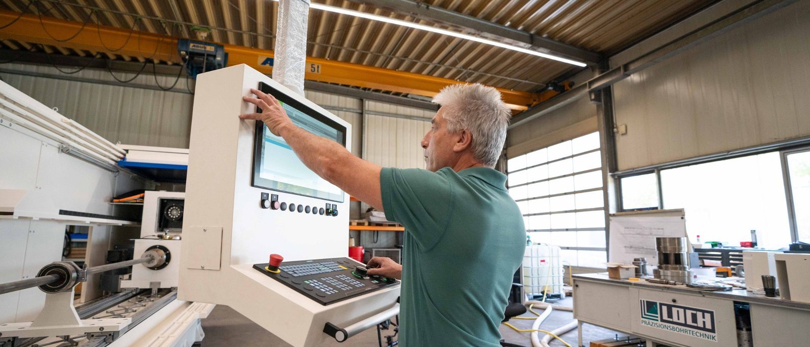 Kollege an einer Tiefbohrmaschine in der Halle in Ergolding